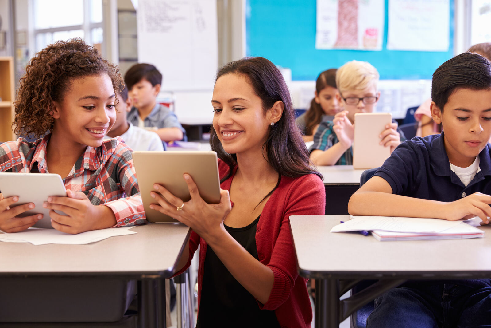 Teacher and students using tablets together in the classroom